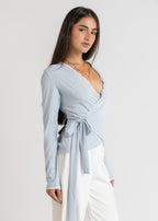 Woman wearing a light blue wrap top with a white background