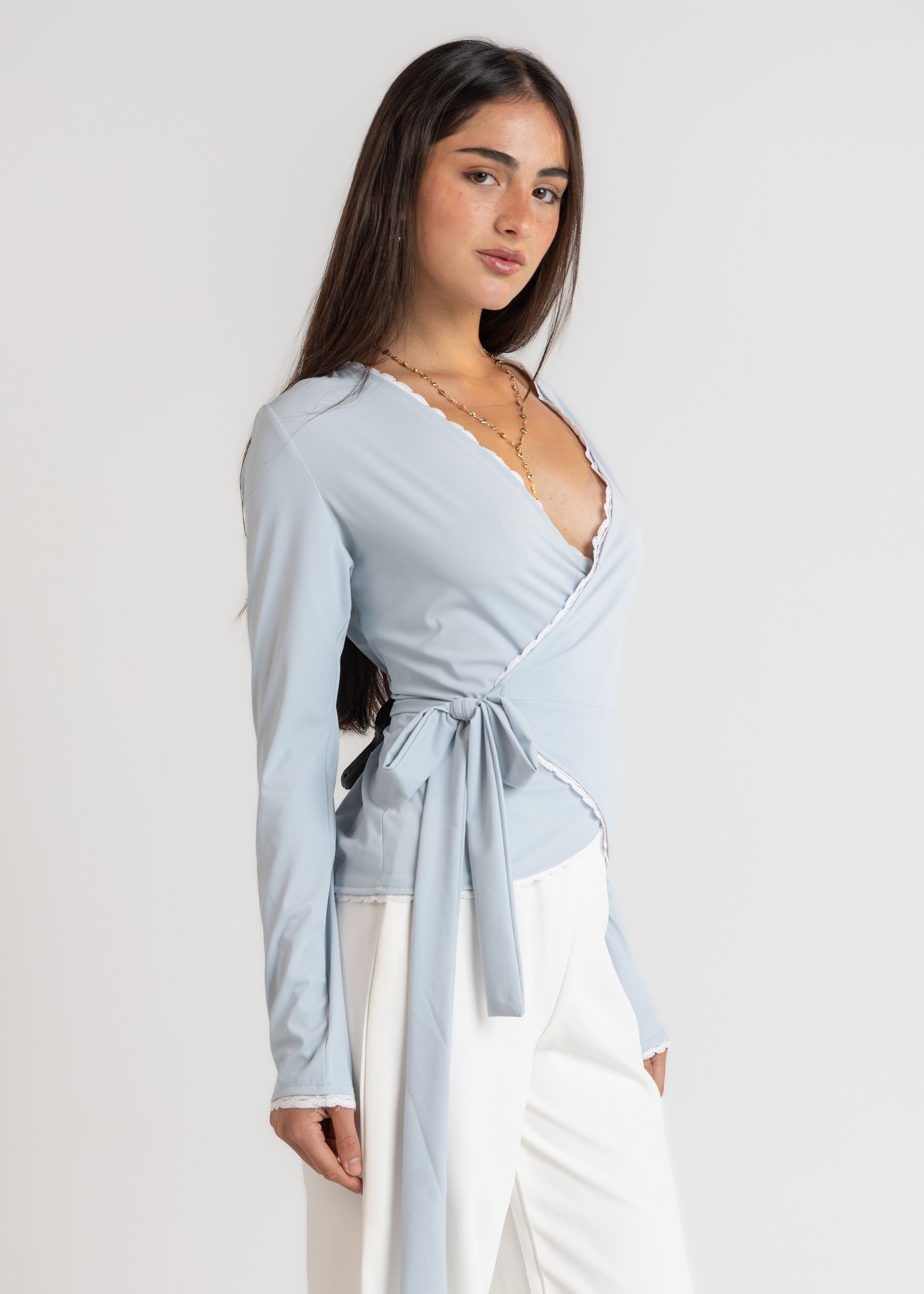 Woman wearing a light blue wrap top with a white background