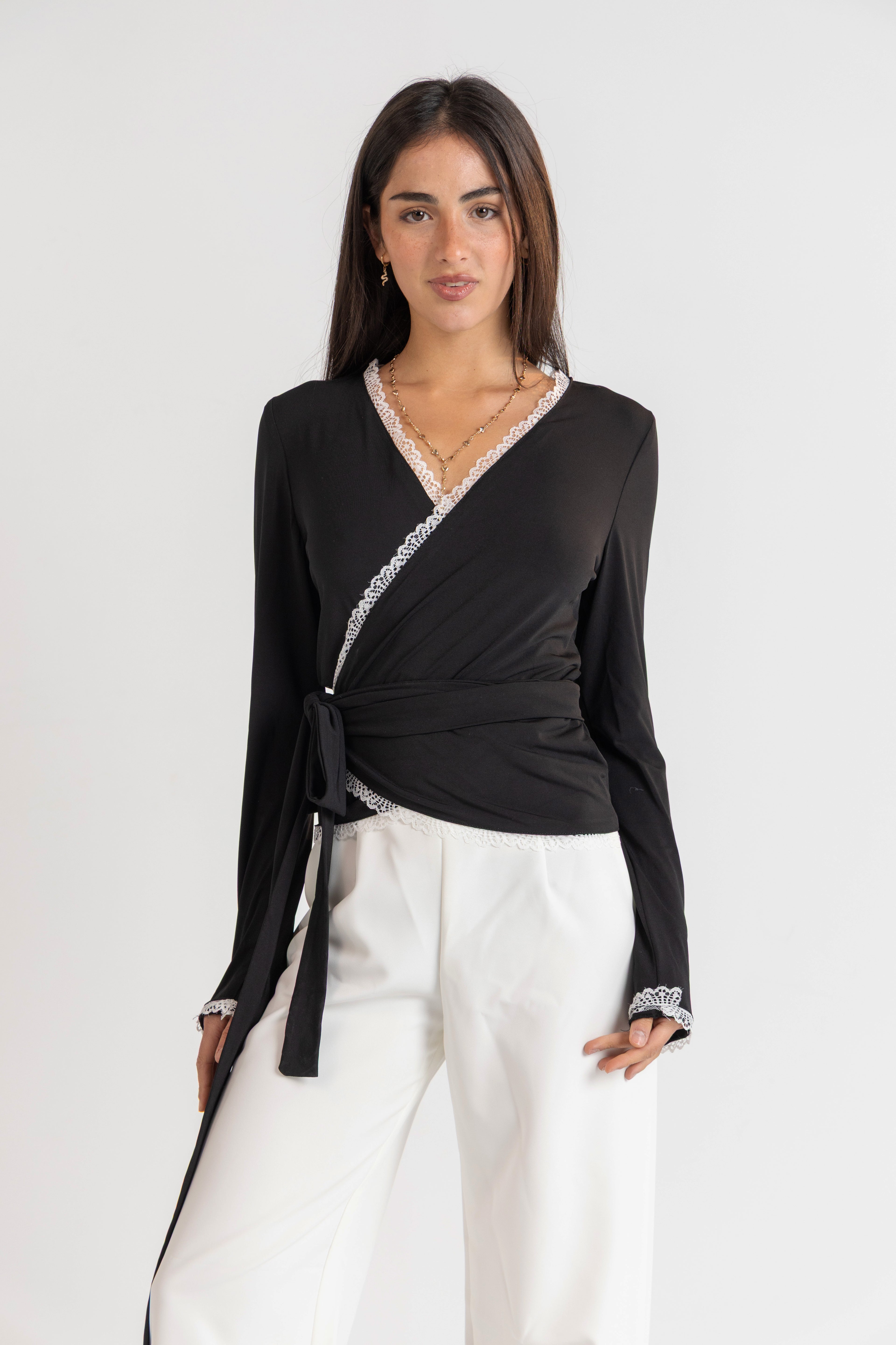 Woman wearing a black top with white trim and white pants on a white background