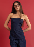 Woman wearing a strapless denim top and pants against a red background