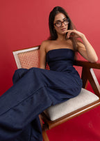 Woman in a strapless navy dress sitting on a chair against a red background