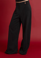 Person wearing black high-waisted pants on a red background