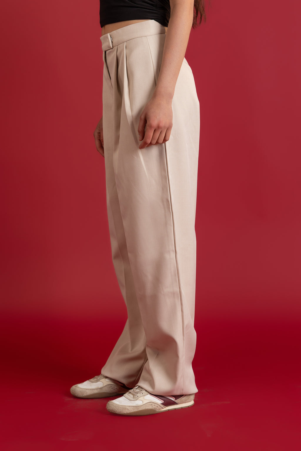 Person wearing beige pants on a red background