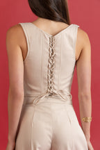 Beige sleeveless dress with a braided back detail on a red background