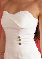 White strapless dress with gold buttons on a blurred background