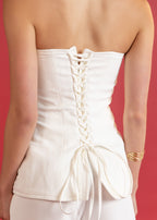 White strapless top with lace-up back on a red background