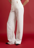 Person wearing a white outfit with high-waisted pants on a red background
