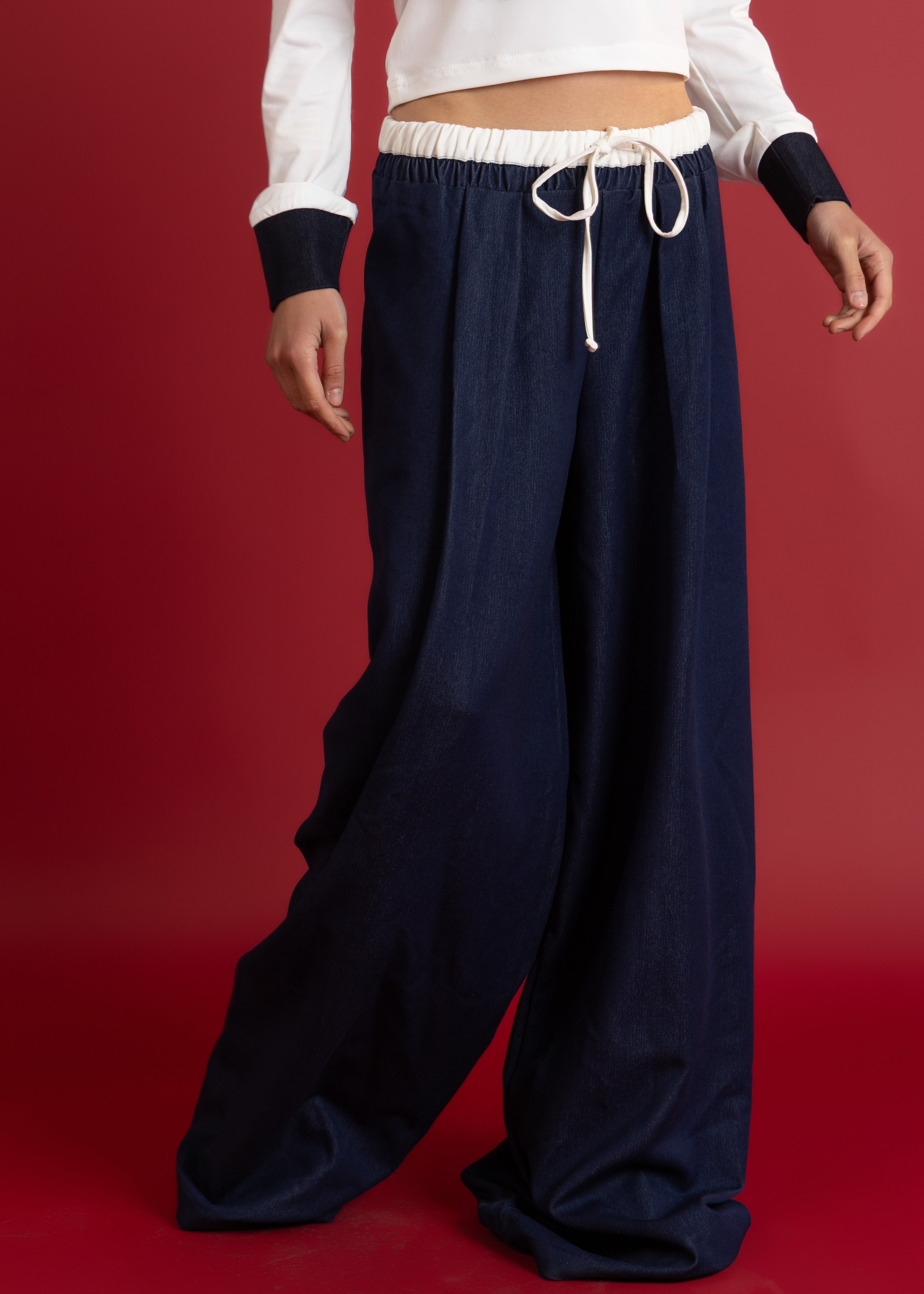Person wearing Denim wide-leg pants and a white top on a red background