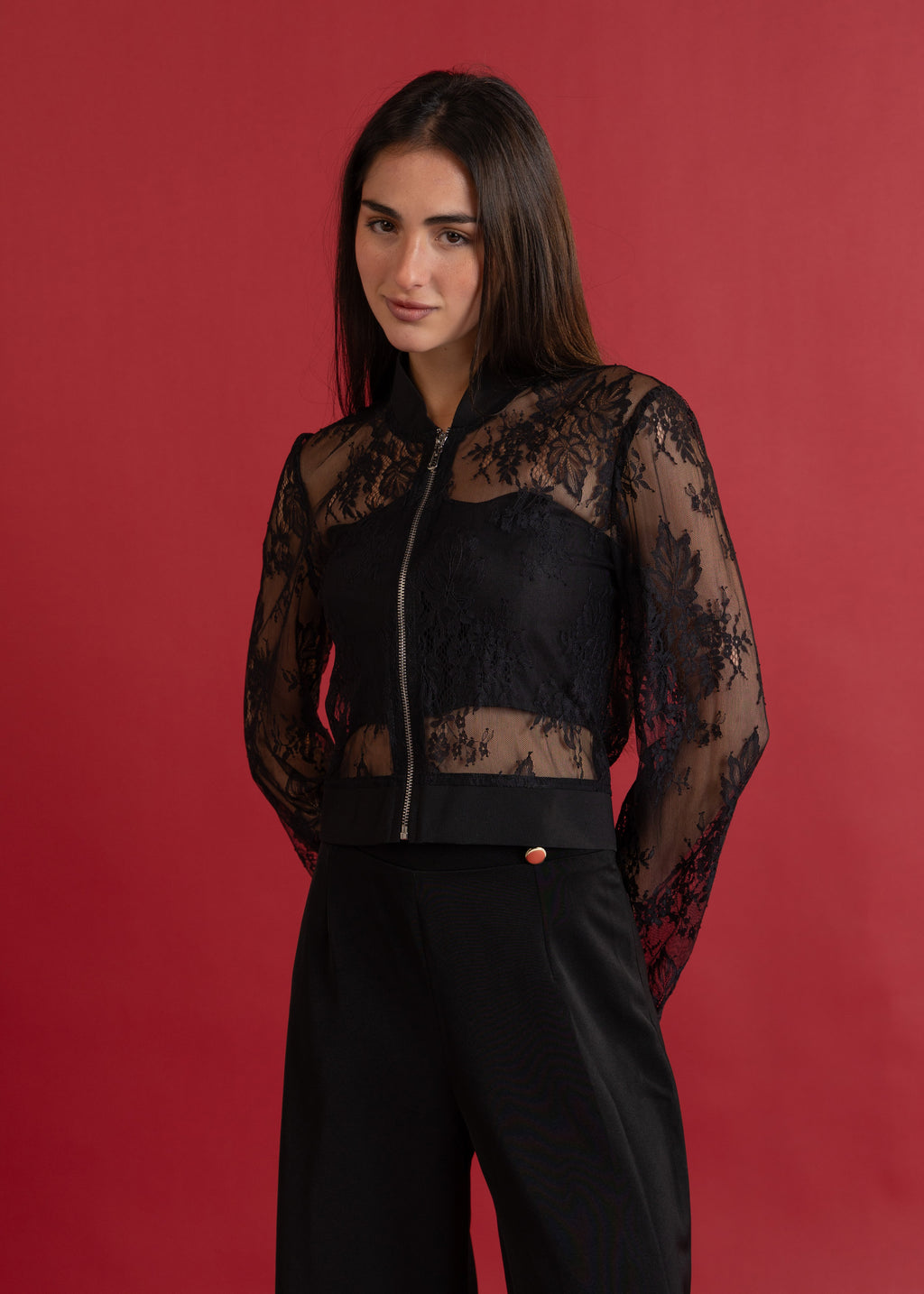 Woman wearing a black lace top against a red background