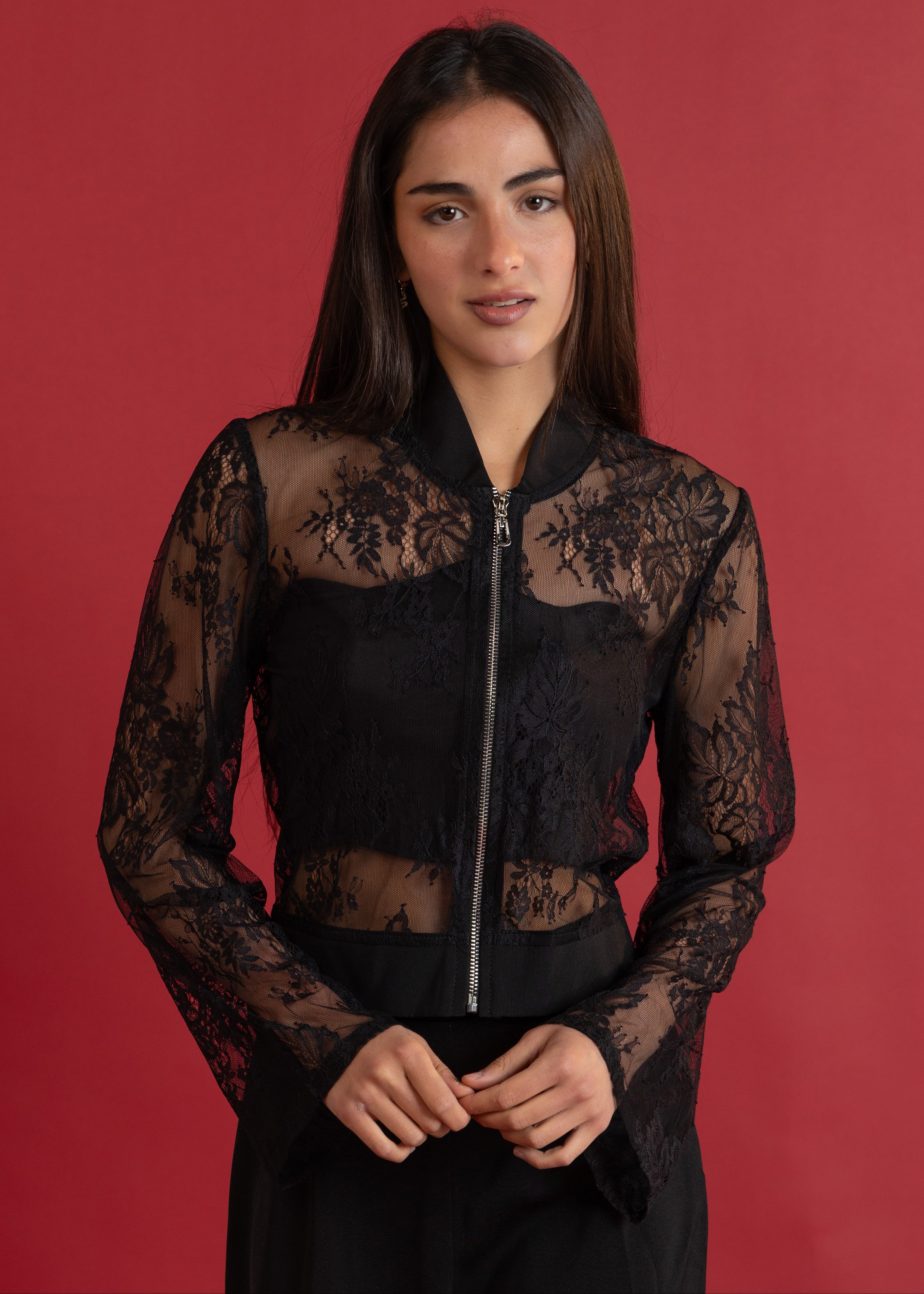 Woman wearing a black lace jacket against a red background