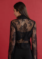 Woman wearing a black lace top against a red background