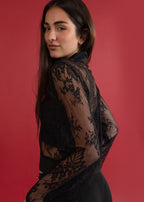 Woman wearing a black lace top against a red background